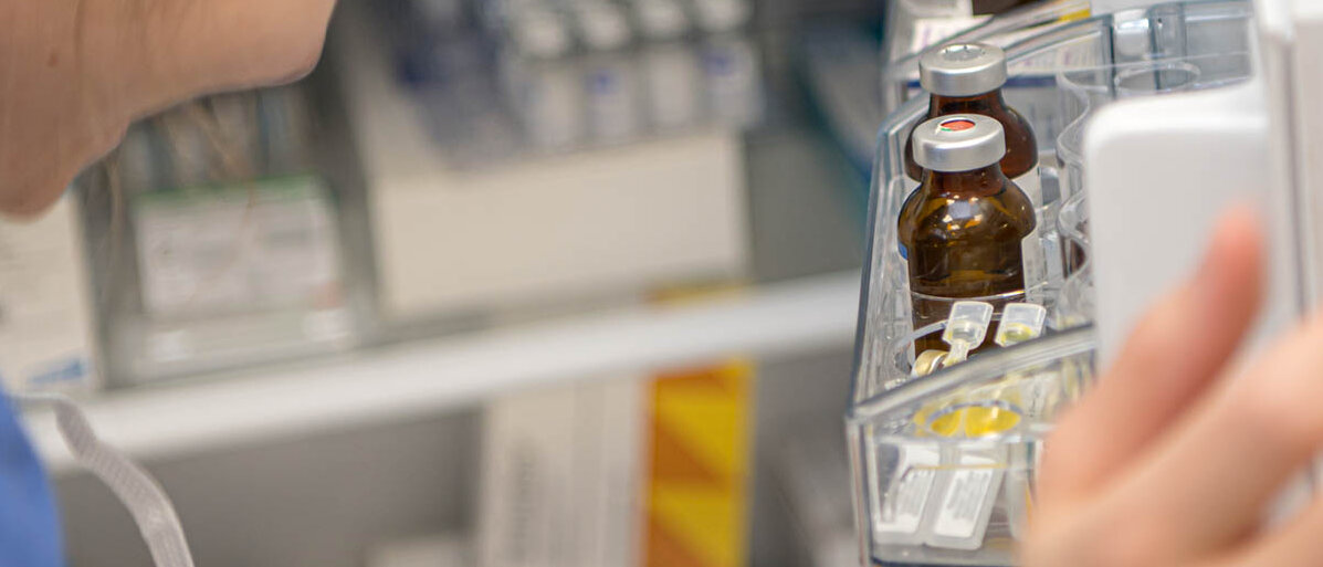 Eine Apothekenmitarbeiterin schaut in den geöffneten Arzneimittelkühlschrank.