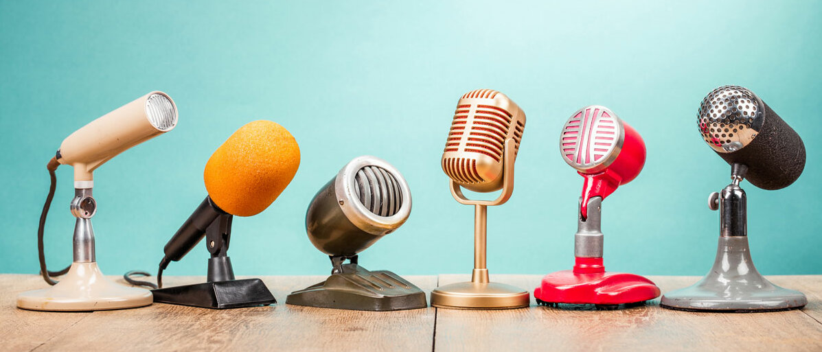 Verschiedene Mikrofone stehen auf einem Sprecherpult.