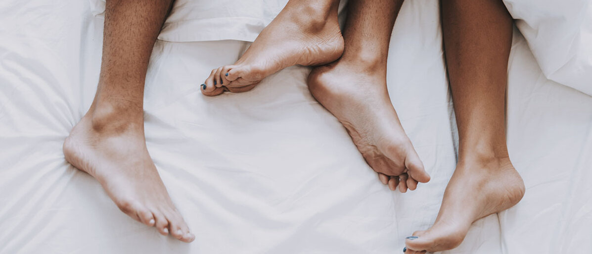 Füße von Mann und Frau schauen unter der Decke hervor