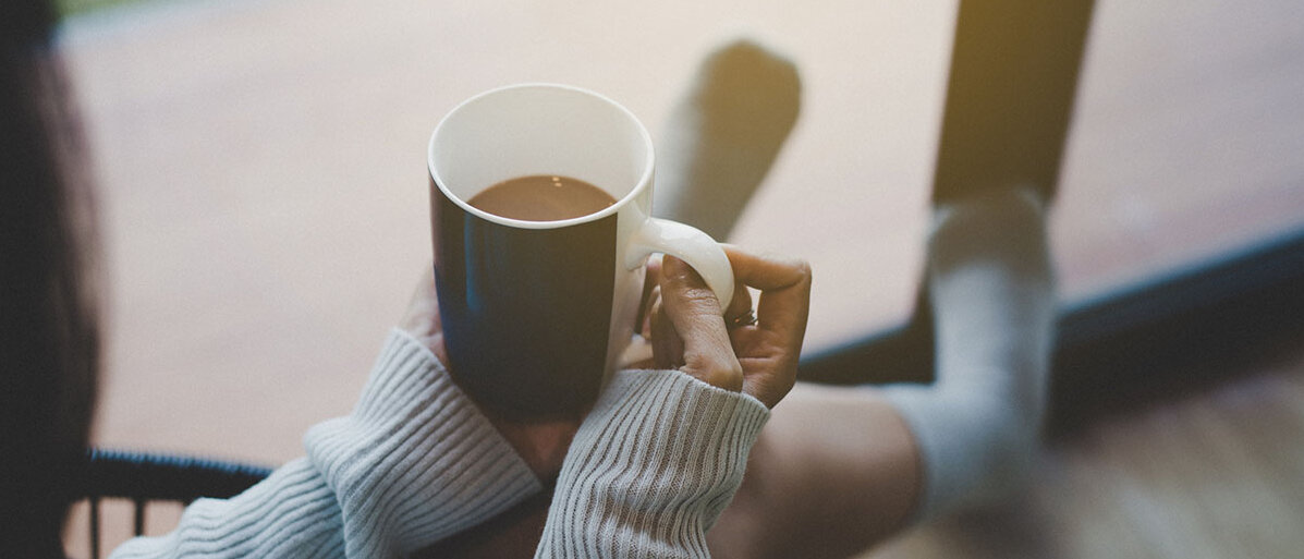 Frau sitzt auf Stuhl und trinken heißen Kaffee.