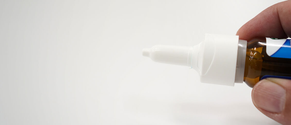Nahaufnähme: Mann hält Nasenspray in Hand auf weißem Hintergrund 