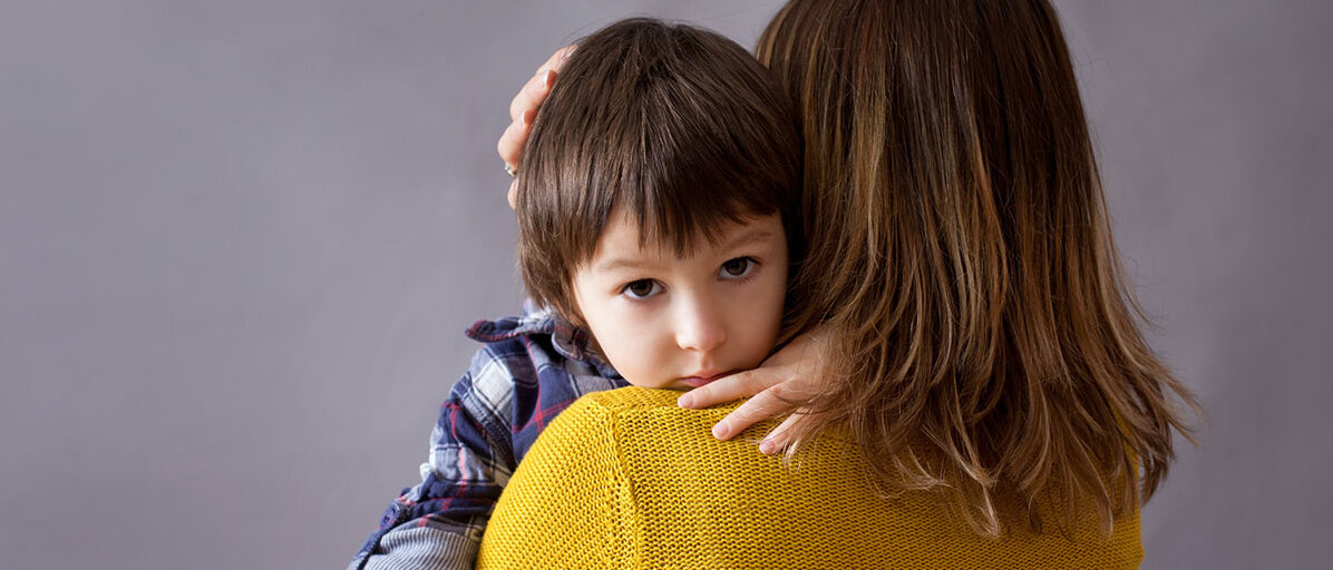 Gefühle bei Kindern Trauriger Junge wird von Mutter in Arm gehalten