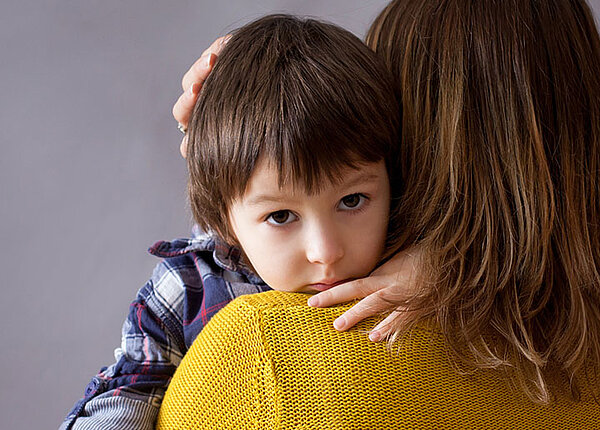 Gefühle bei Kindern Trauriger Junge wird von Mutter in Arm gehalten