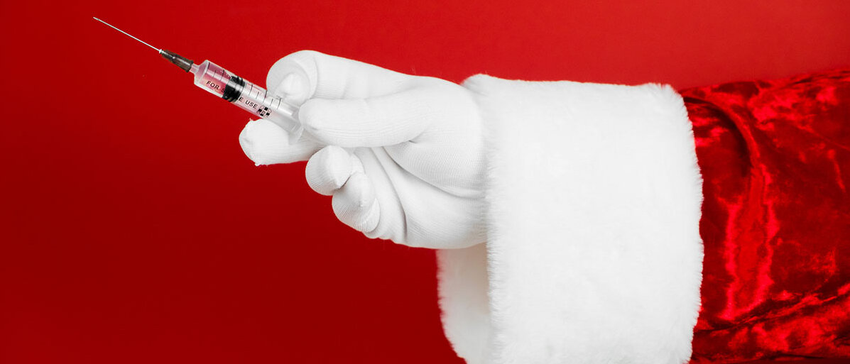 Grippeschutzimpfung vor den Feiertagen Weihnachtsmann hält Impfung hoch