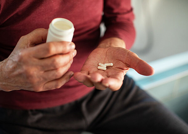 Nahrungsergänzungsmittel für Senioren & Seniorinnen Älterer Mann mit Pillen und Pillendose in der Hand
