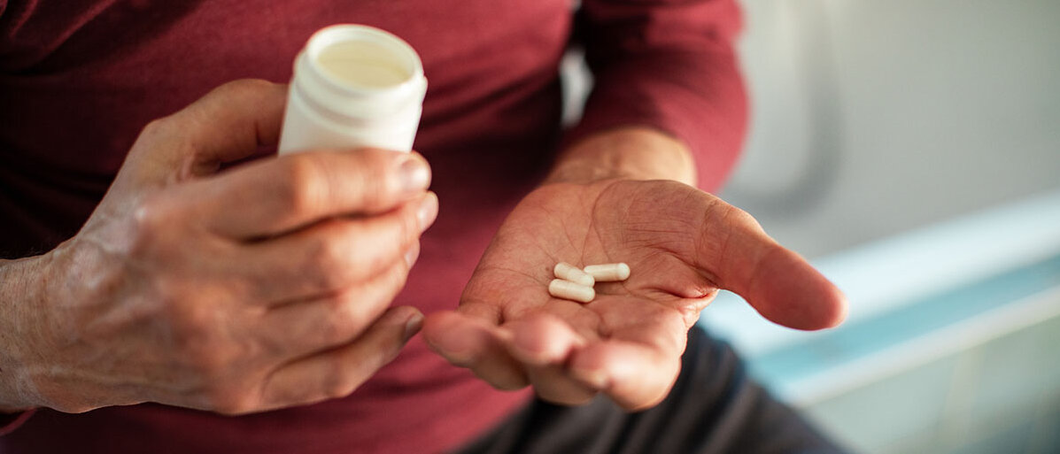 Nahrungsergänzungsmittel für Senioren & Seniorinnen Älterer Mann mit Pillen und Pillendose in der Hand