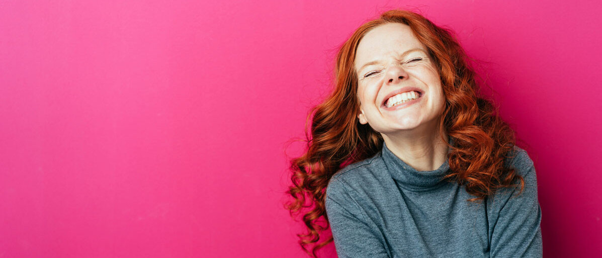 Frau lacht auf rosa Hintergrund