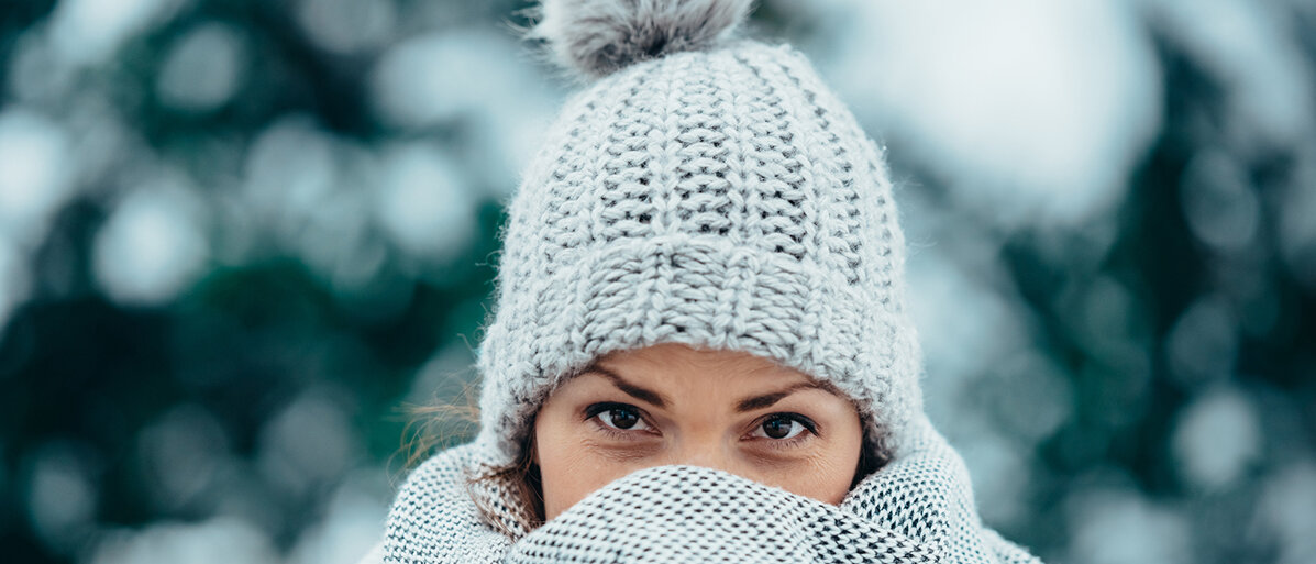 Eine Frau mit Mütze und Schal im Schnee - man sieht nur ihre Augen