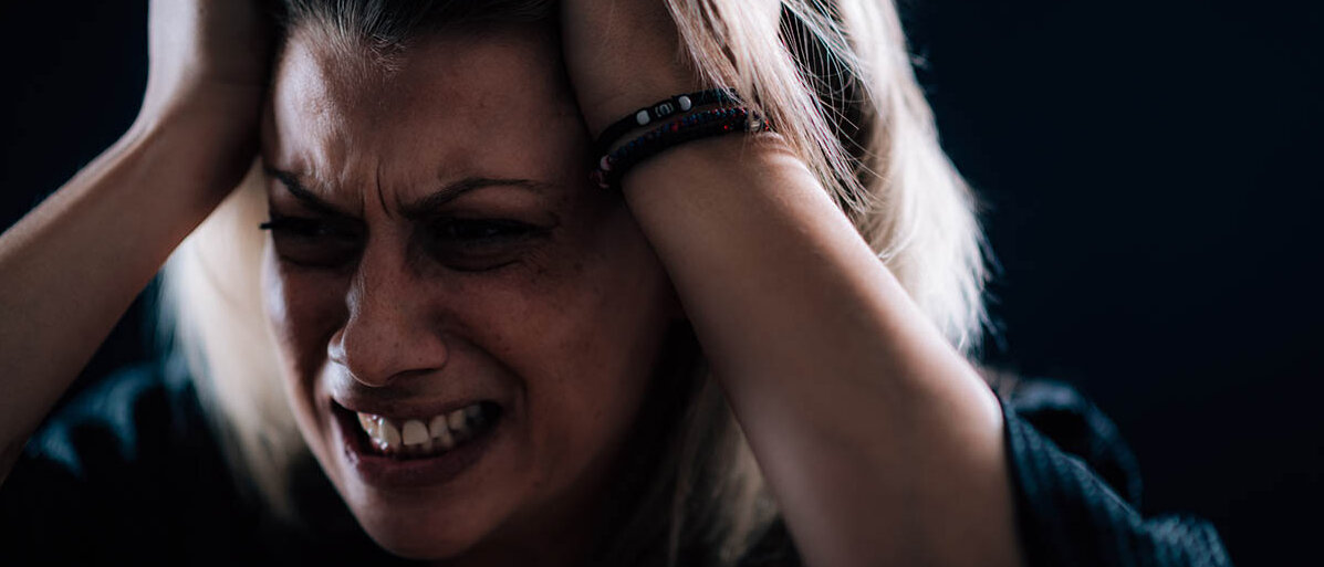 Borderline-Persönlichkeitsstörung: Hintergründe, Behandlung und Skills : Eine Frau rauft sich die Haare und verzieht das Gesicht zu einer fletschenden, verzweifelten Grimasse.