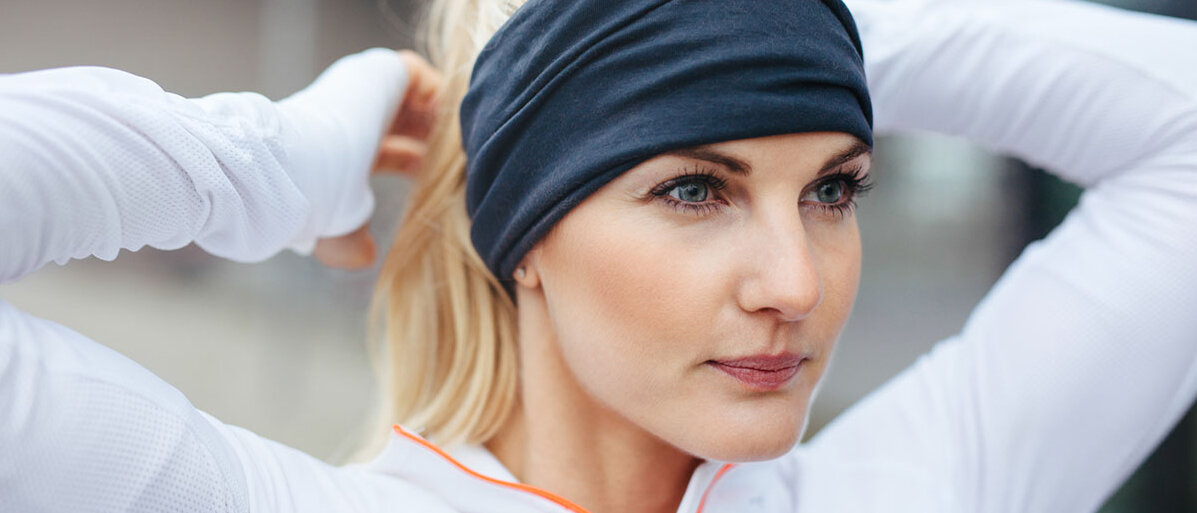 Schutz vor Schweiß Sportliche Frau trägt Stirnband, dass die Ohren überdeckt