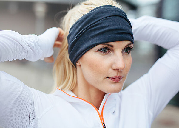 Sportliche Frau trägt Stirnband, dass die Ohren überdeckt 