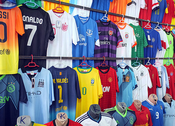 viele bunte Fußballtrikots hängen an einem Marktstand nebeneinander