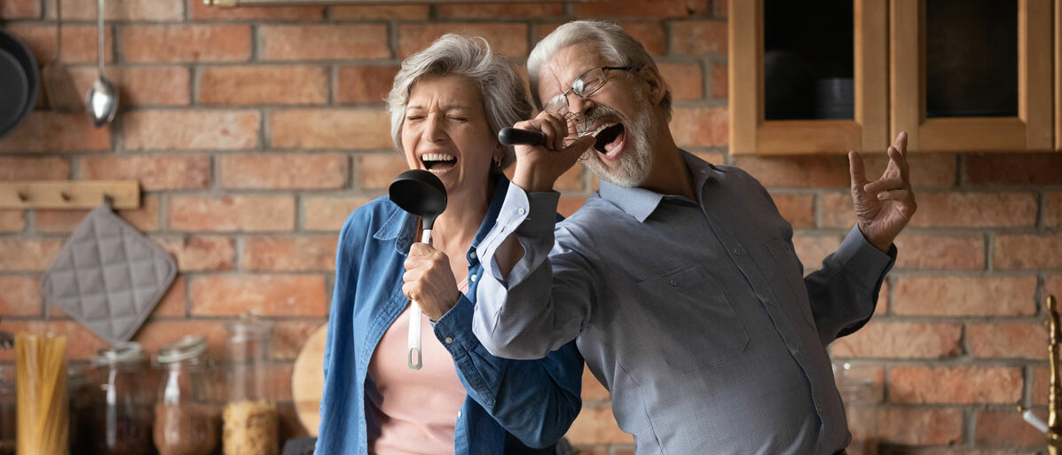 Älteres Ehepaar singt gemeinsam in der Kueche