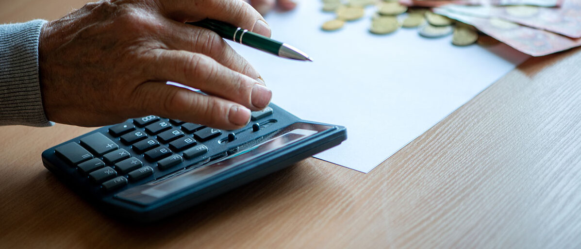 Altersvorsorge ab 50: RentenlĂŒcke berechnen HĂ€nde eines Seniors mit Taschenrechner und Geldscheinen