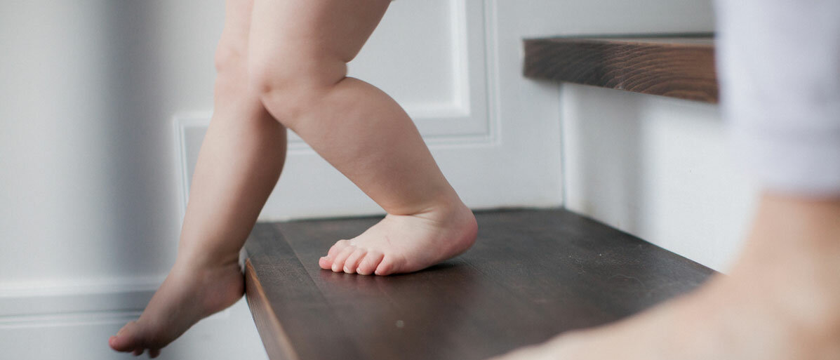 Kleines Kind läuft mit nackten Füßen die Treppe herunter