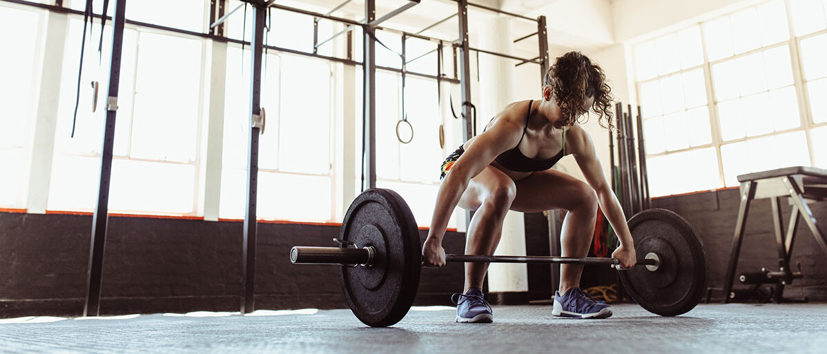 Krafttraining statt Cardio Frau in Open Gym an Langhantel