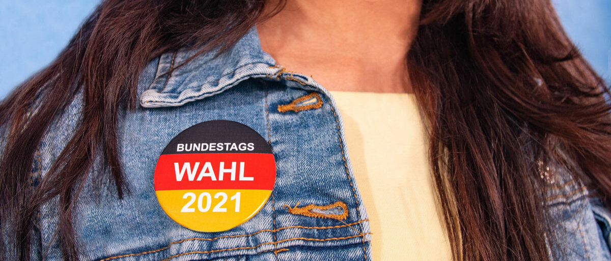 Eine junge Frau trägt an ihrer Jacke einen Button in schwarz, rot und gold mit der Aufschrift "Bundestagswahl 2021".