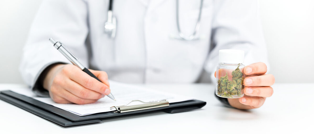 Strengere Regeln für Medizin-Cannabis Arzt in Kittel füllt Formular aus und hält dabei Glas mit Cannabis-Blüten in der Hand