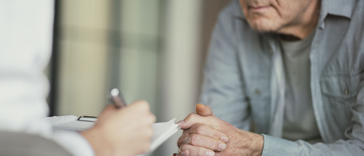 Ist eine Psychotherapie sinnvoll? Arzt spricht mit Patient und macht sich Notizen
