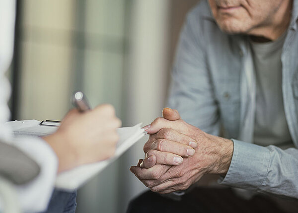 Arzt spricht mit Patient und macht sich Notizen