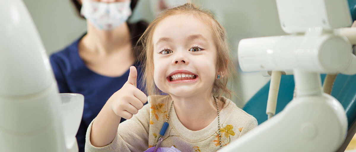 Ein Kind grinst auf einem Zahnarztstuhl