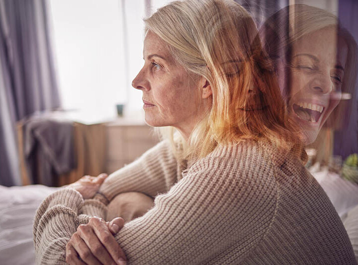 : Eine Frau um die 60 sitzt teilnahmslos auf dem Sofa. Hinter ihrem Kopf ist ihr Gesicht noch einmal angedeutet, hier lacht sie haltlos.