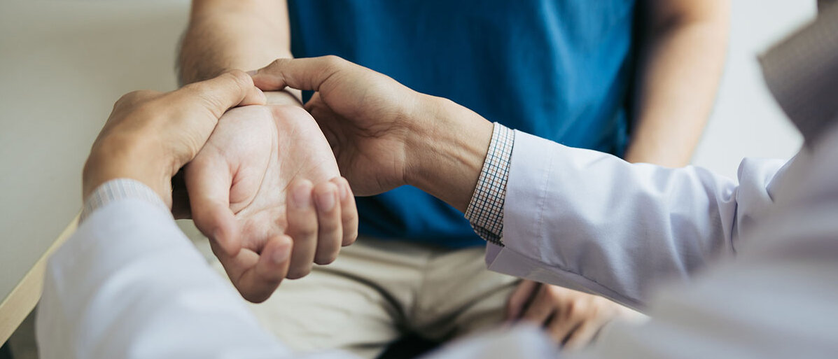 Beschwerden im Handgelenk Arzt untersucht das Handgelenk eines Mannes