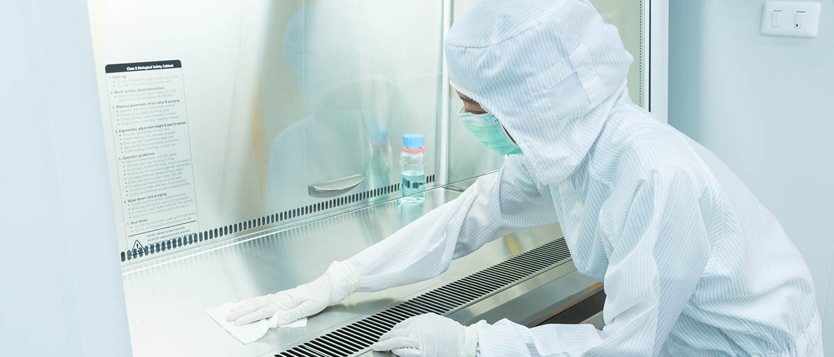 Sterile Arzneiformen: Sterilisation und Sterilisationsverfahren in der Apotheke Eine Frau in Schutzkleidung reinigt eine Laminar-Air-Flow-Bank.