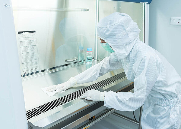Sterile Arzneiformen: Sterilisation und Sterilisationsverfahren in der Apotheke Eine Frau in Schutzkleidung reinigt eine Laminar-Air-Flow-Bank.