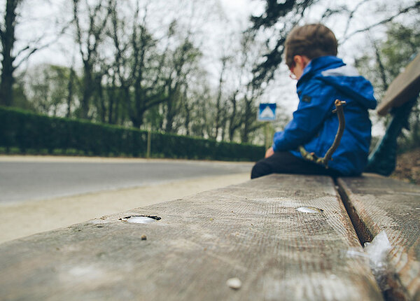 Trauriger Junge auf Holzbank