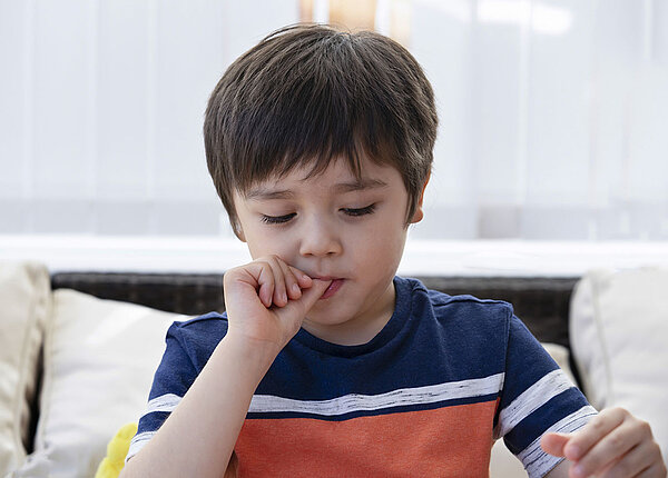 Kleiner Junge beißt auf seinen Fingernägeln