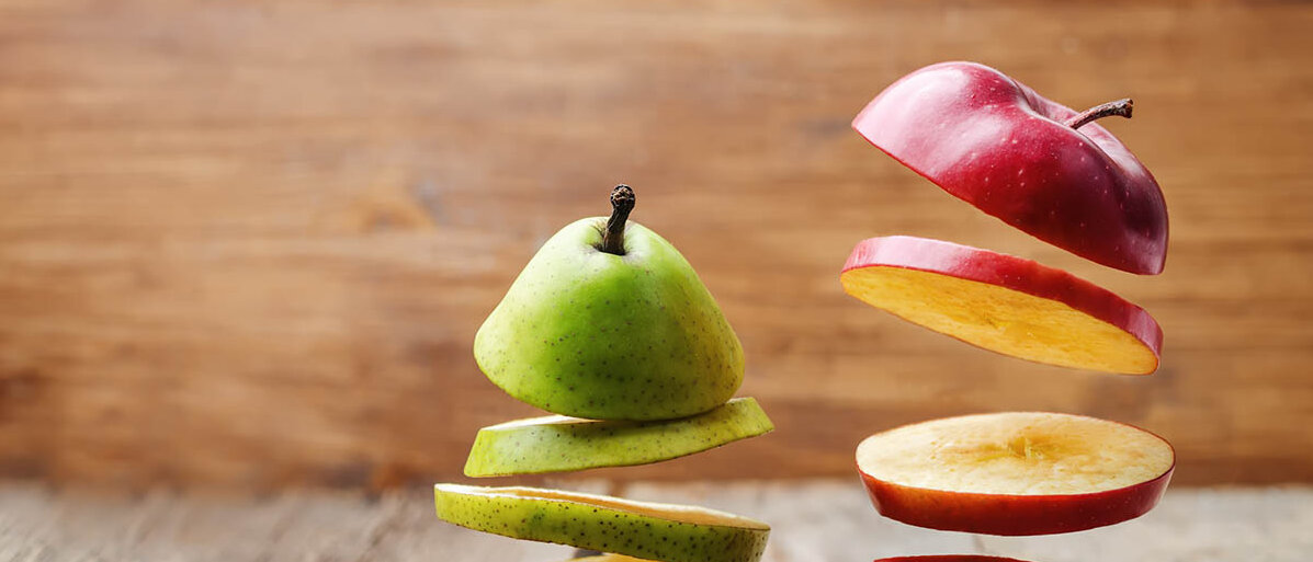 Ein Apfel und eine Birne sind in Scheiben geschnitten. Die Scheiben schweben übereinander.