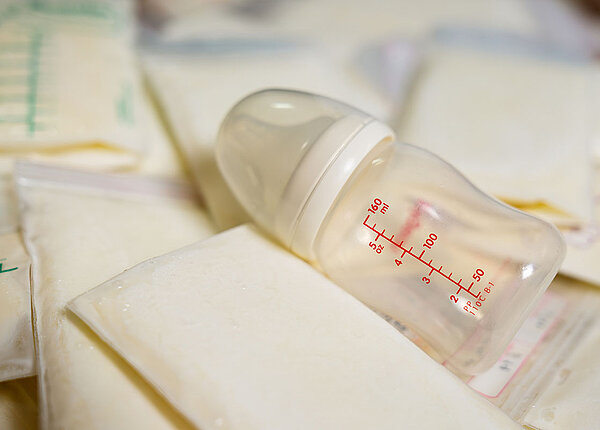 Beutel mit gefrorener Muttermilch und darauf eine leere Flasche 