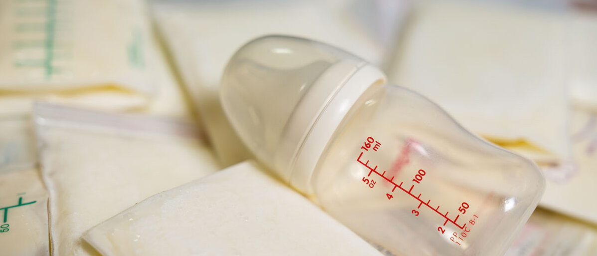 Beutel mit gefrorener Muttermilch und darauf eine leere Flasche 