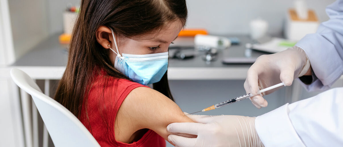 Kleines Mädchen mit Maske bekommt Impfung