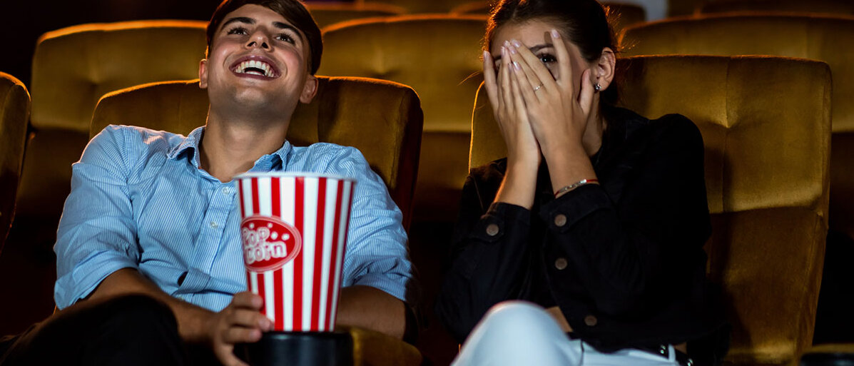 Lachender Mann und sich fürchtende Frau im Kino