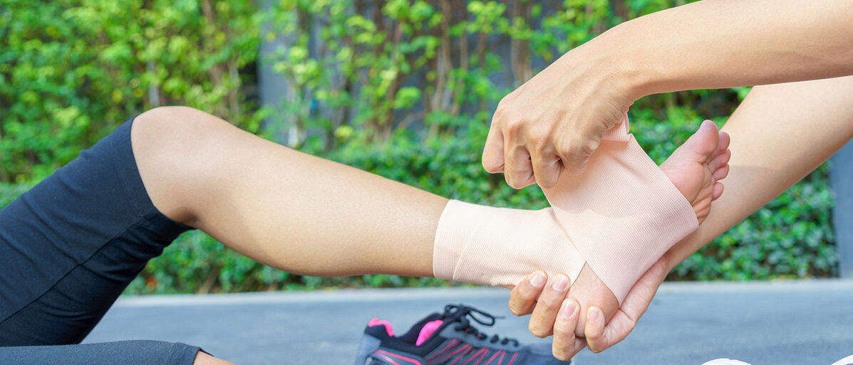Bänderdehnung am Fuß Verletzter Fuß einer Frau wird bandagiert.