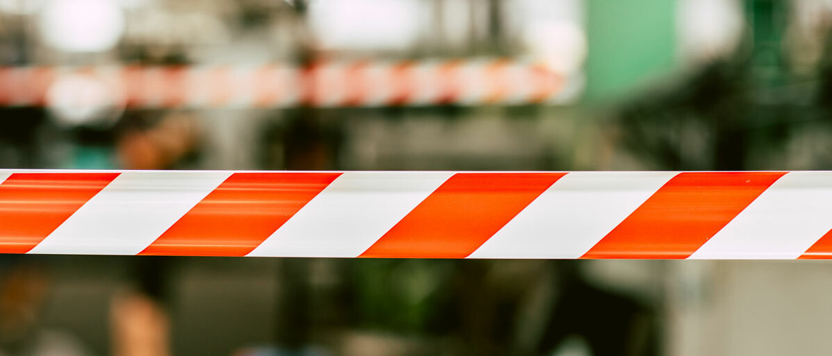 Ein nur verschwommen erkennbarer Arbeitsbereich ist mit Flatterband abgesperrt.