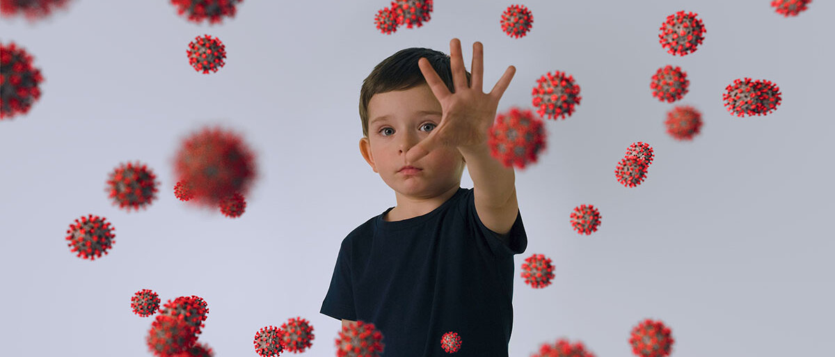 Ein Junge streckt abwehrend die Hand aus. Um ihn herum schwirren zahlreiche animierte Corona-Viren.