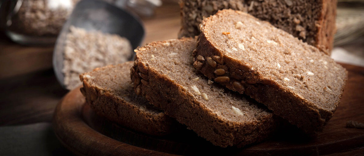 aufgeschnittenes Vollkornbrot auf einem Brettchen mit Körnern