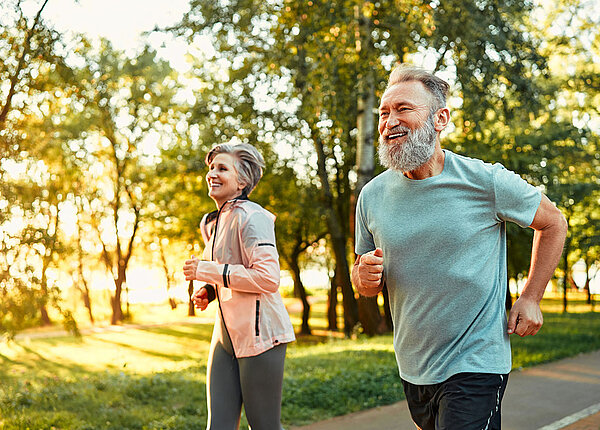 Älteres Paar joggt gemeinsam durch einen Park