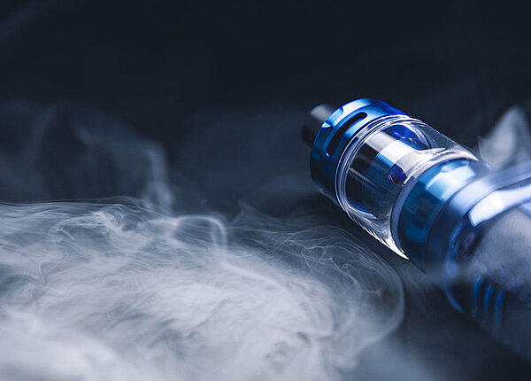 Eine E-Zigarette liegend und drum herum ist jede Menge Rauch