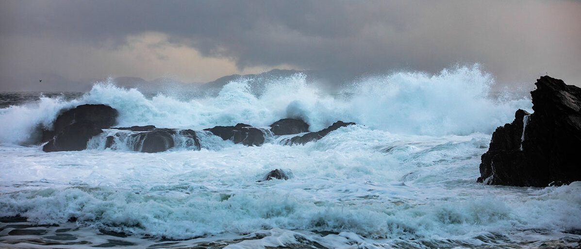Konflikte und Stress im Beruf meistern Felsen in stĂĽrmischer See, an dem die Wellen abprallen.