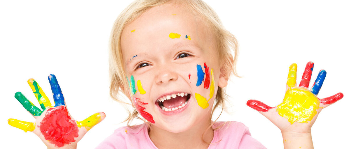 Lachendes Mädchen deren Finger voller Farbe ist.