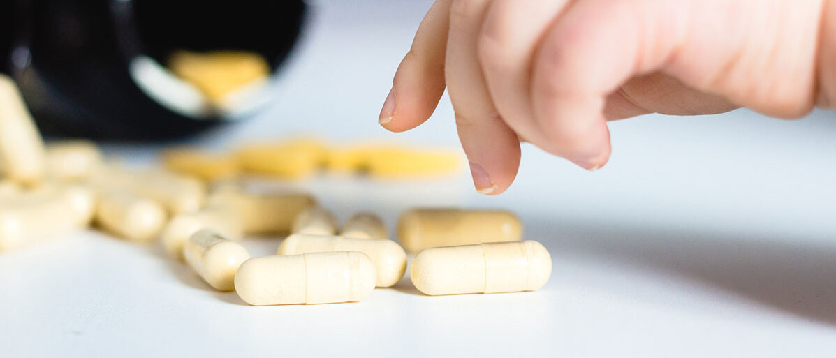 Tabletten verschluckt Hand eines Kleinkindes greift nach Kapseln.