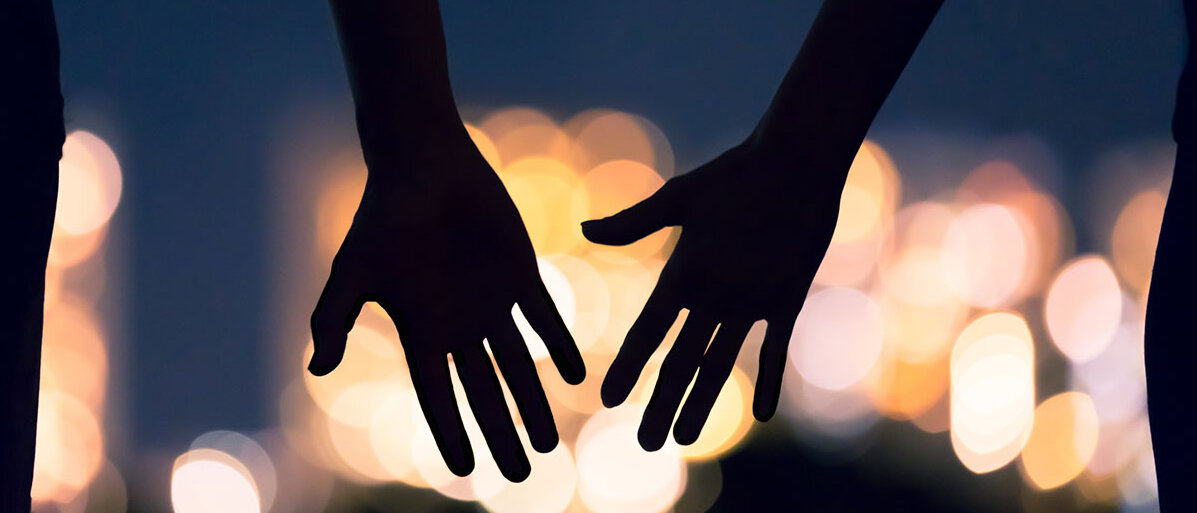 Die Silhouette zweier Hände, die sich annähern 