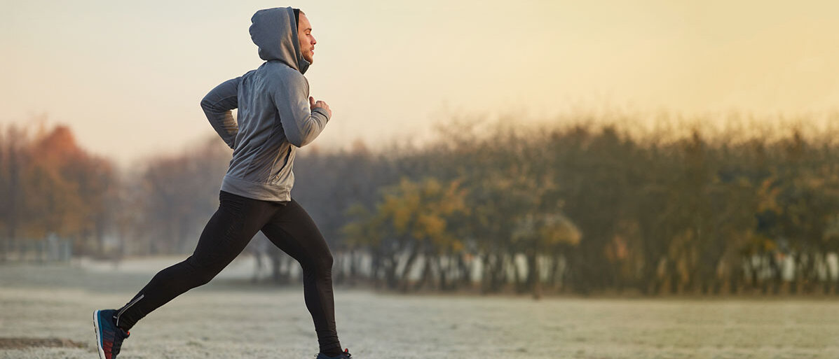 Sport im Herbst und Winter. Mann joggt in einem Park.. Es herrschen kalte Temperaturen.