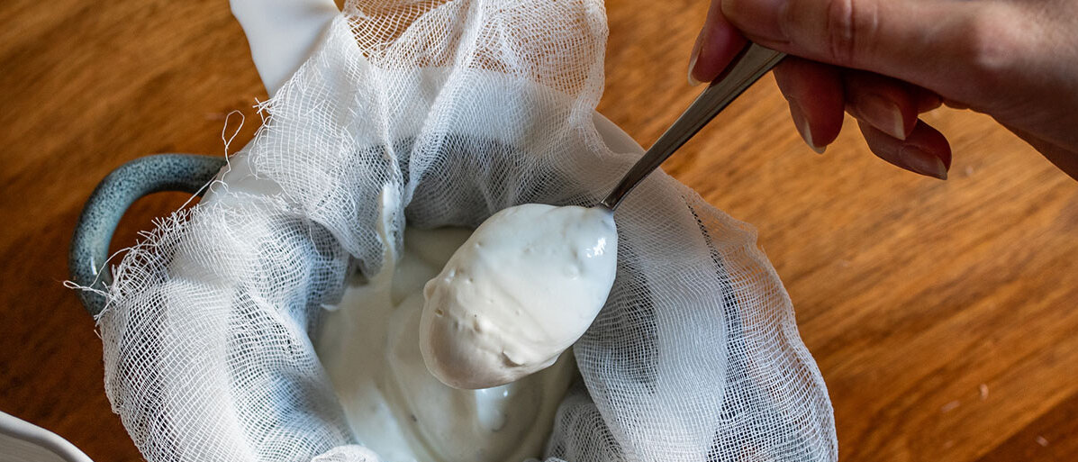 Frau die Skyr selbst macht und durch ein Tuch/Sieb gibt 