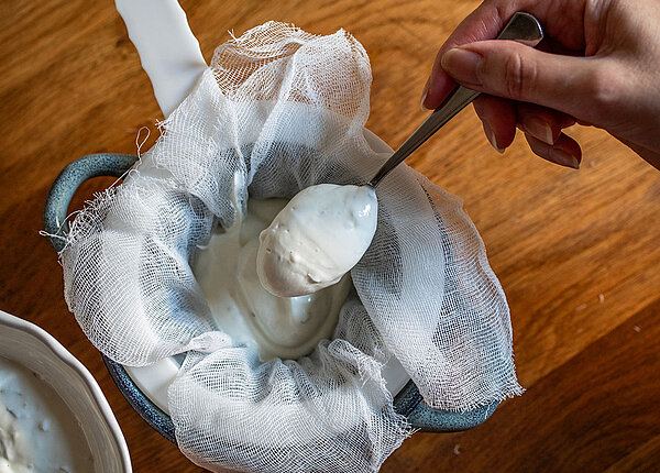 Frau die Skyr selbst macht und durch ein Tuch/Sieb gibt 