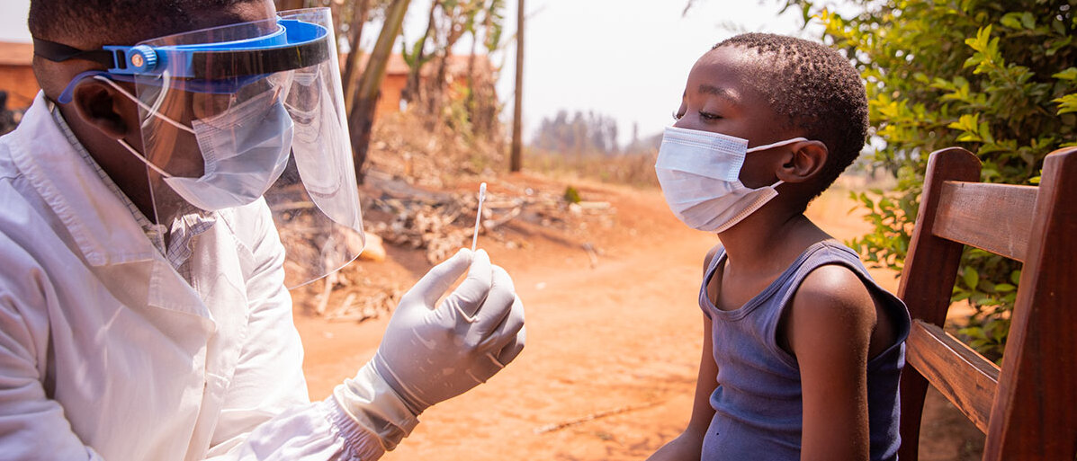 Ebola-Ausbruch Ein Arzt hält einen Tupfer in der Hand. Er trägt eine Maske und das Kind, dass ihm gegenüber sitzt, trägt einen Mundschutz